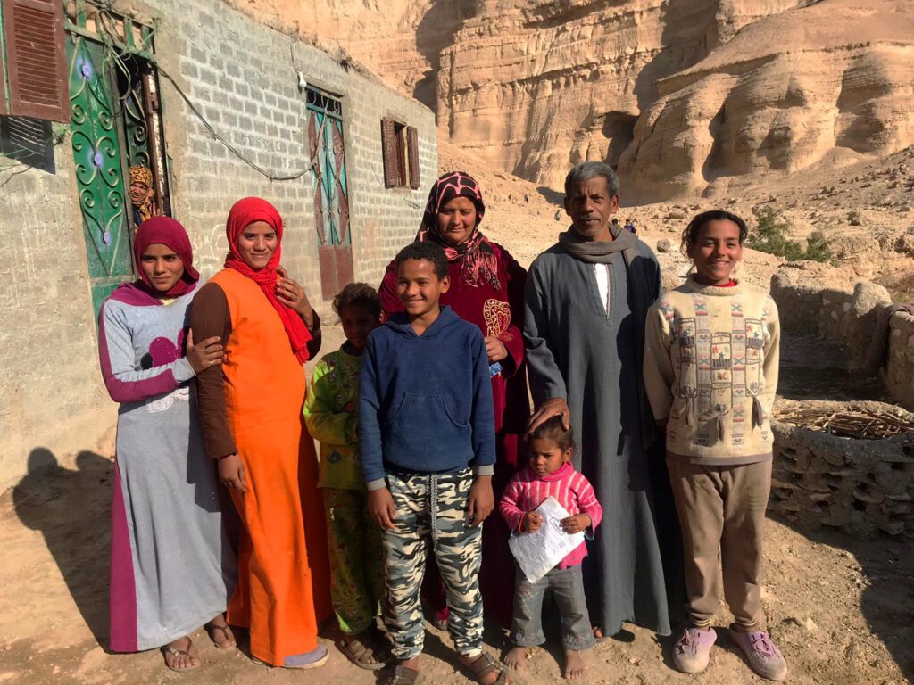 A Bab Amal program participant and her family pose for a photo out front of their home in Bani Wasel, Sohag governorate, Egypt.