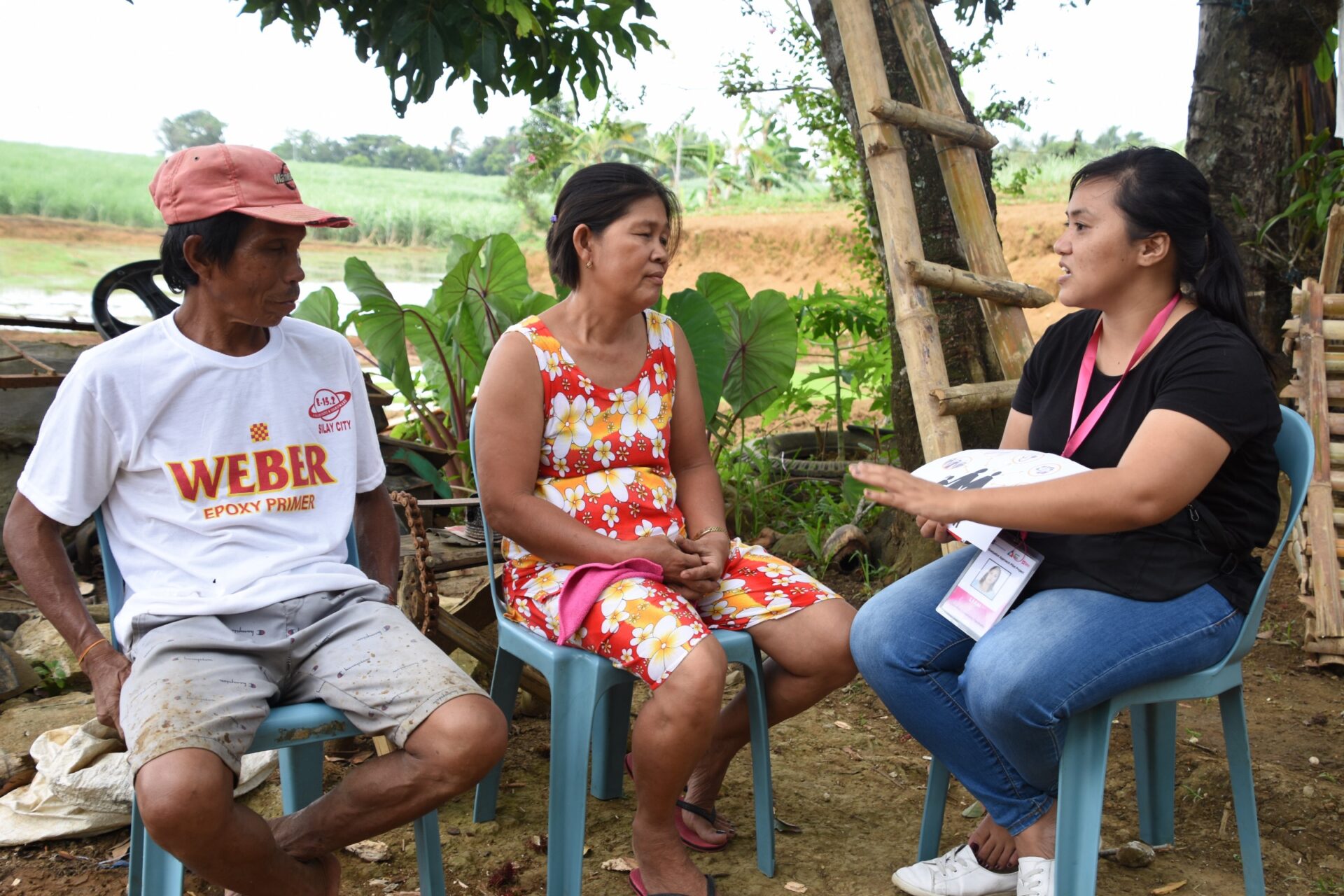 A Graduation Community Facilitator (GCF) in Negros Occidental province, Philippines works with a program participant and her husband on life-skills and business training.