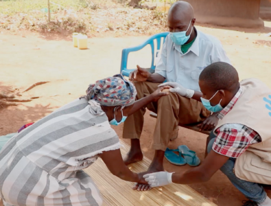 Humanity Inclusion staff working with an individual in the field during COVID-19